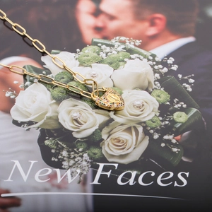 Gold paperclip chain necklace with colorful zircon heart locket on a magazine background