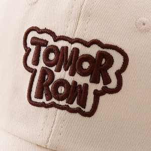 Beige cotton baseball cap featuring 3D TOMORROW embroidery with brown bubble lettering