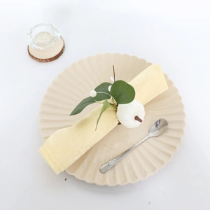 White pumpkin napkin ring with eucalyptus leaves on a yellow textile napkin in a beige plate