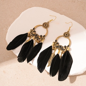 Bohemian bronze hoop earrings with black feathers and leaf charms on stone tray