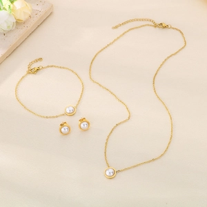 Detailed set of gold shell pearl necklace, bracelet and earrings on beige silk fabric