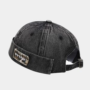 Close-up of black washed denim brimless docker cap with metal buckle and embroidery