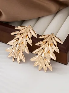 Nahaufnahme der goldenen Ginkgoblatt-Ohrringe mit mehrlagiger Metallstruktur auf Seide