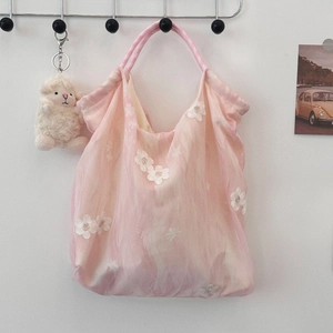 Close-up of pink tie-dye tote bag with white flower embroidery and plush lamb charm