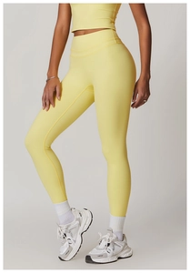 Detail of high-waist yoga pants in pale yellow with matte brushed fabric and elastic support