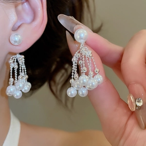 Close-up of elegant pearl tassel earrings with silver chains and glossy finish