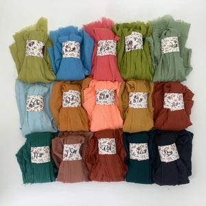 Detail view of cotton viscose pleated scarves in 15 vibrant colors with floral paper bands