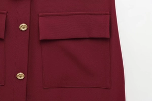 Detail of wine red crepe fabric featuring a pocket flap and decorative gold buttons