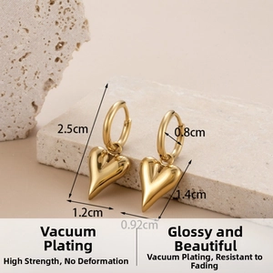 Detailed view of gold heart pendant earrings with measurements on a stone display