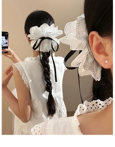 Détail de la pince à cheveux en dentelle blanche avec nœud noir sur cheveux de femme