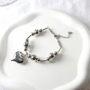 Silver bead bracelet with large heart pendant on elegant white display tray