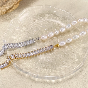 Macro detail of elegant pearl bracelet featuring rectangular zircons and gold chain links