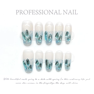 Detail of handmade press-on nails with white base, blue glitter, and crystal rhinestones