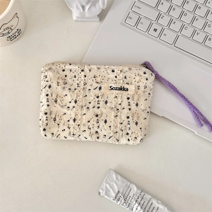 Detailed top view of a cream floral makeup bag with lace trim on a minimalist workspace