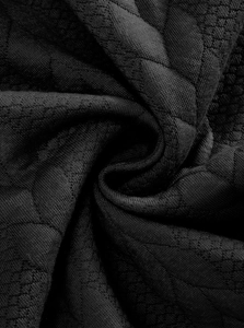 Macro close-up of heavy black jacquard knit fabric showing premium texture and density