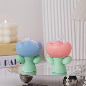 Detail of pink and blue tulip scented candles on mirror tray with pearl chain decoration