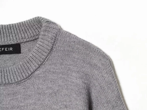 Close-up detail of grey wool knit sweater featuring precise stitching on crew neckline