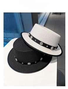 Close-up of woven straw boater hats with pearl and metallic rivet decorative bands