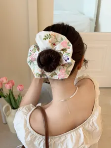 Detail of embroidered floral scrunchie on hair bun featuring satin texture and fruit patterns