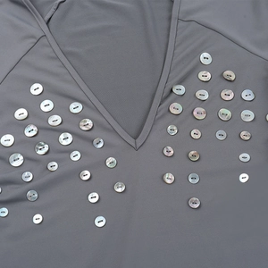 Vue détaillée des boutons en nacre irisés sur une robe grise cintrée à col en V
