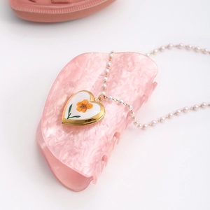 Vue détaillée du collier médaillon cœur avec fleurs séchées et pince à cheveux marbrée