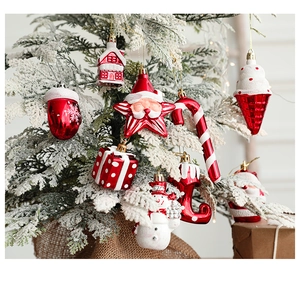 Close-up of red and white Christmas ornaments hanging on a snowy festive tree branch