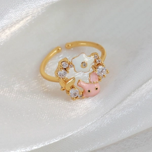 Detailed close-up of a gold ring with pink enamel bunny, white flower, and cubic zirconia
