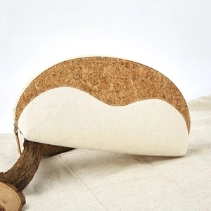 Detail of semi-circle cork and canvas eyewear pouch resting on a natural wooden branch