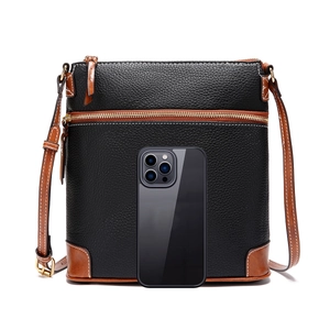 Detail of black pebble leather crossbody bag with brown trim next to a smartphone for scale
