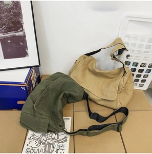 Detail of soft beige and army green canvas messenger bags with adjustable straps