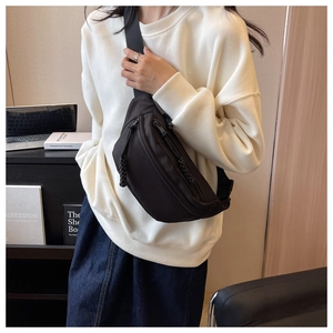 Close-up of black canvas waist bag with textured woven zipper pull and crossbody strap