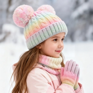Close-up of kids winter knit set with rainbow gradient pattern and faux fur pom-poms