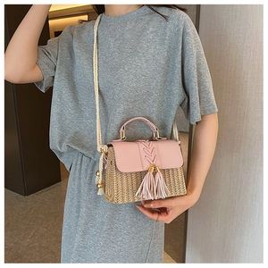 Detail of hand-woven straw crossbody bag featuring a pink leather flap and decorative tassel