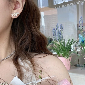 Elegant floral pearl earrings with gold plating and zircons worn by a model in a garden