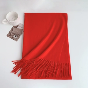 Flat lay of soft red cashmere-like scarf with fringe tassels and lifestyle props