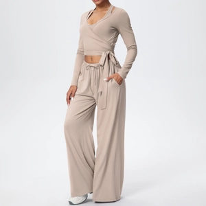 Détail d'un haut cache-cœur beige avec lien latéral et pantalon en tricot à jambes larges