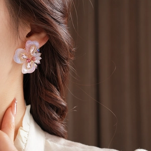 Gros plan détaillé d'une boucle d'oreille fleur avec cristaux roses sur l'oreille