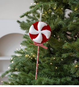 Close-up of a red and white glitter swirl lollipop ornament hanging on a Christmas tree