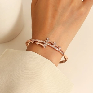 Dettaglio di un bracciale rigido oro rosa con cuori di strass indossato su un polso elegante