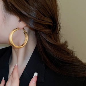 Detailed close-up of chunky gold hoop earrings with polished finish on model