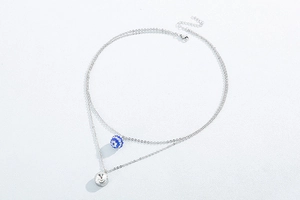 Detail of silver double-layer necklace with blue sphere and round white crystal pendant