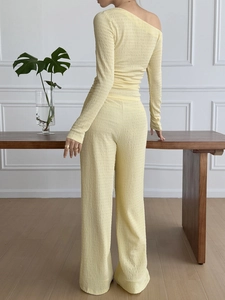 Rear view of yellow textured two-piece set featuring off-shoulder top and wide-leg trousers