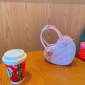Detail of pink heart-shaped PVC jelly bag with quilted diamond pattern on wooden table