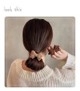 Detail of plush bow hair scrunchie set in cream and brown on a low ponytail