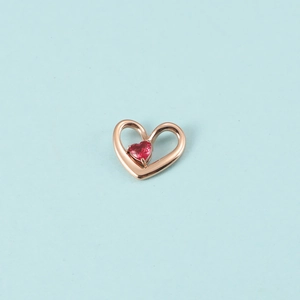 Détail d'un pendentif cœur creux en or rose avec pierre de naissance rouge pour bijoux