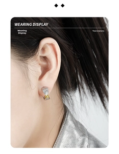 Close-up of a two-tone knot C-shape earring on a model with metallic outfit