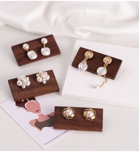 Macro shot of pearl earrings collection on dark walnut wood jewelry display board
