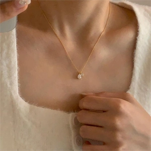 Detail of a gold waterdrop zircon necklace shown on a model neck at collarbone height