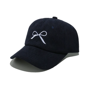 Dark blue corduroy baseball cap with white embroidered bow on white background