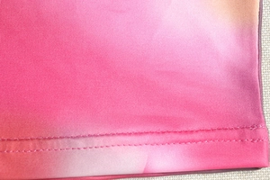 Détail macro du tissu dégradé rose avec couture double aiguille sur l'ourlet bas